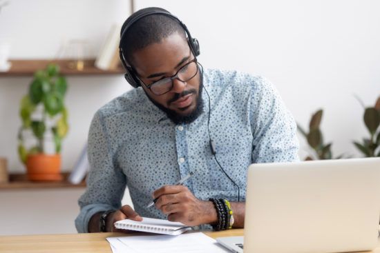 a man wearing headphones is sitting at a desk in front of a laptop computer .