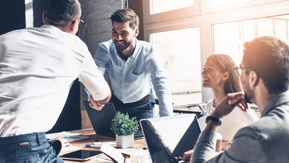 a group of business people are shaking hands in an office .
