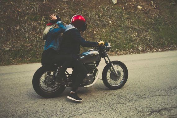 a man and a woman are riding a motorcycle down a road .