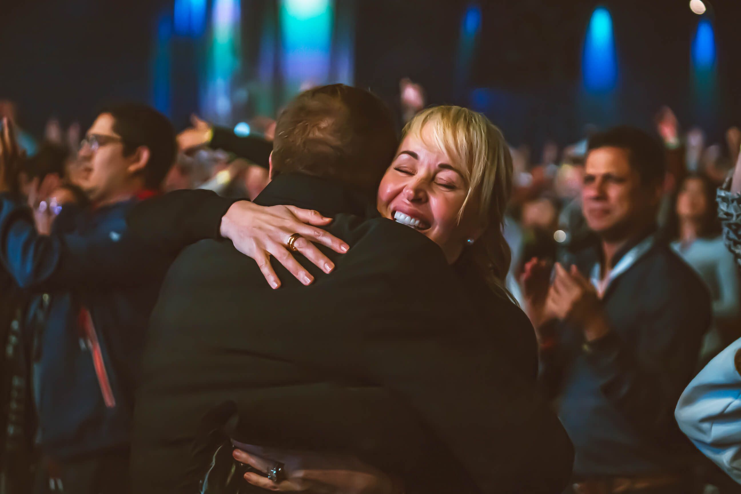 a woman is hugging a man in a crowd of people at a concert .