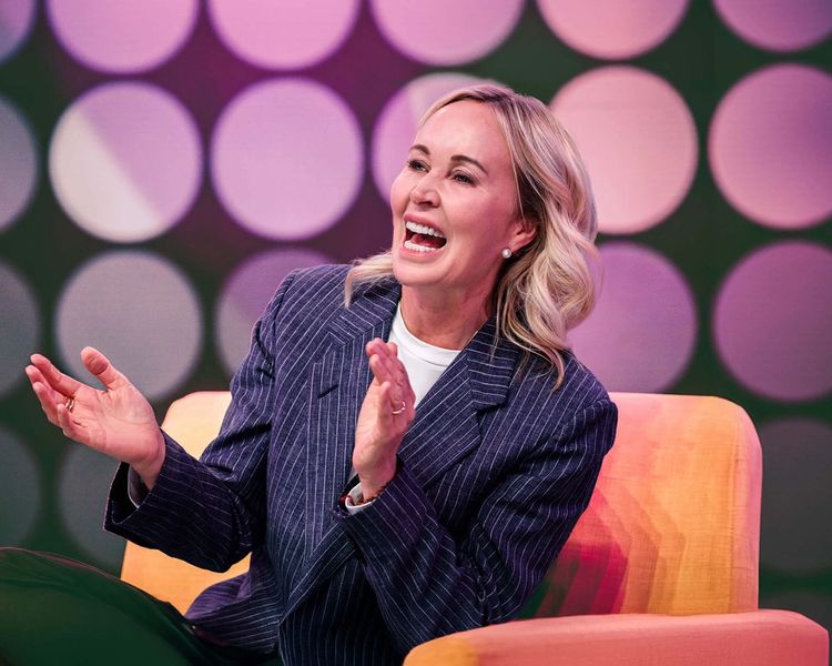 a woman is sitting in a chair with her hands folded and smiling .