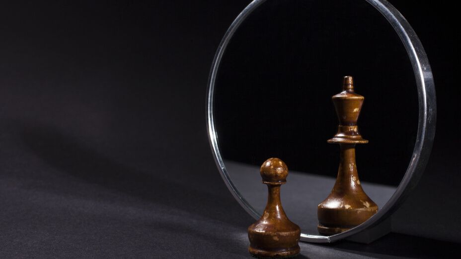a king and queen chess piece are reflected in a mirror .