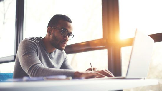 a man is sitting at a table using a laptop computer .