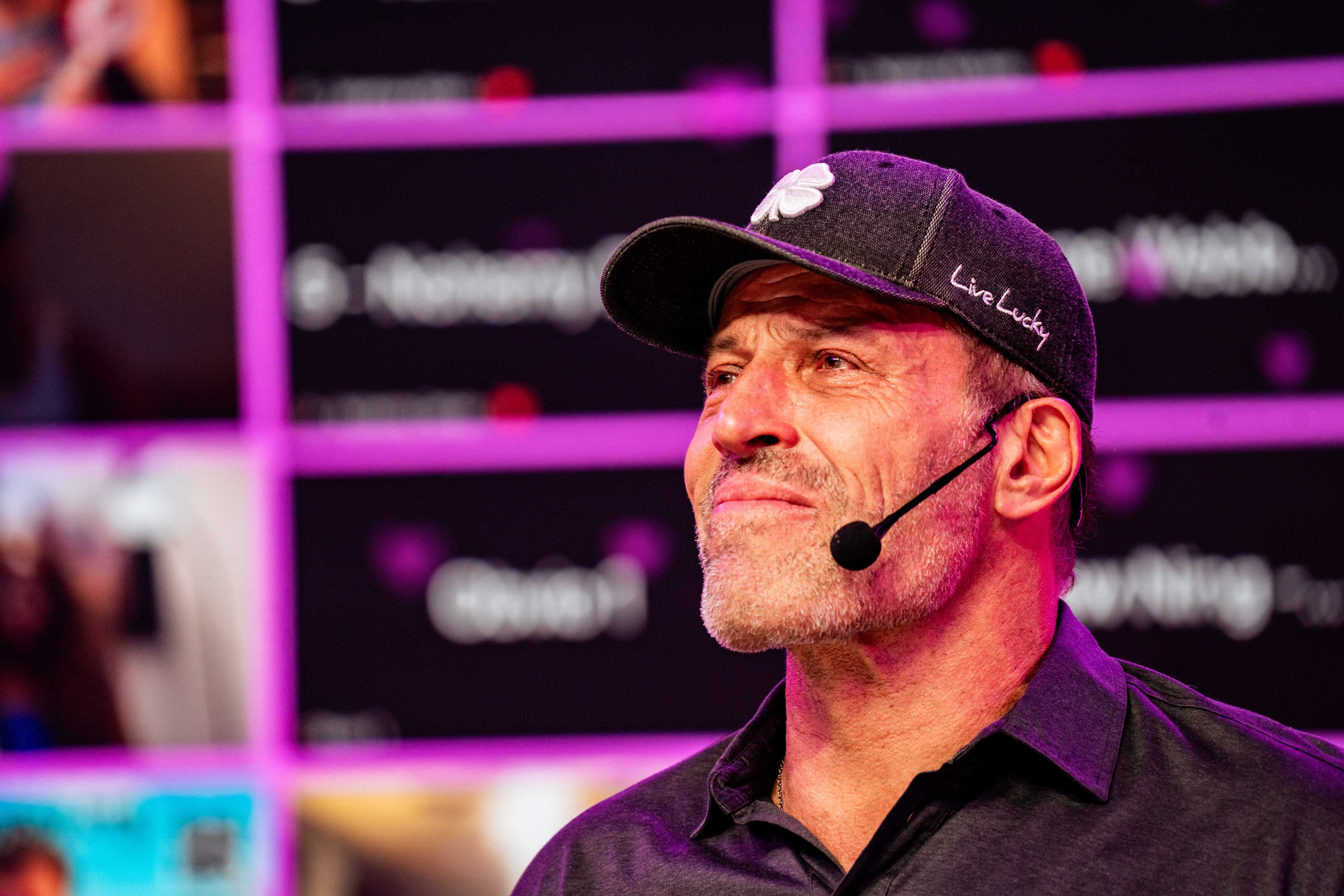 a man wearing a hat and a microphone is standing in front of a purple wall .
