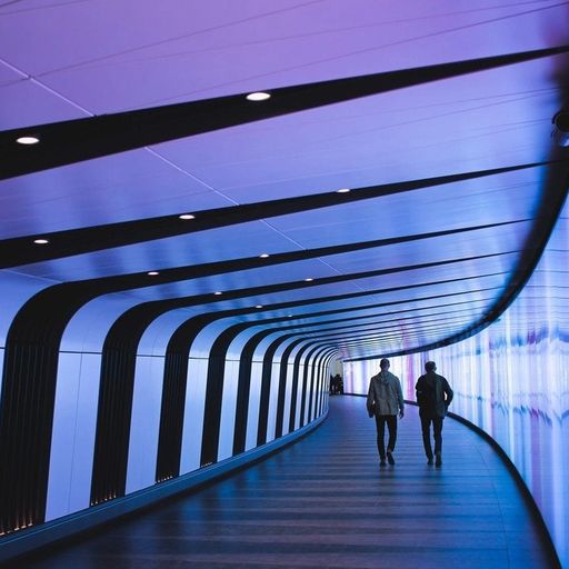 two men are walking through a purple and blue tunnel .