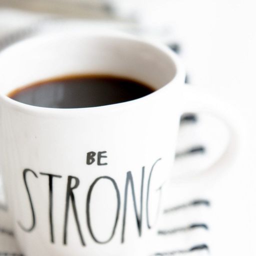a cup of coffee with the words `` be strong '' written on it .