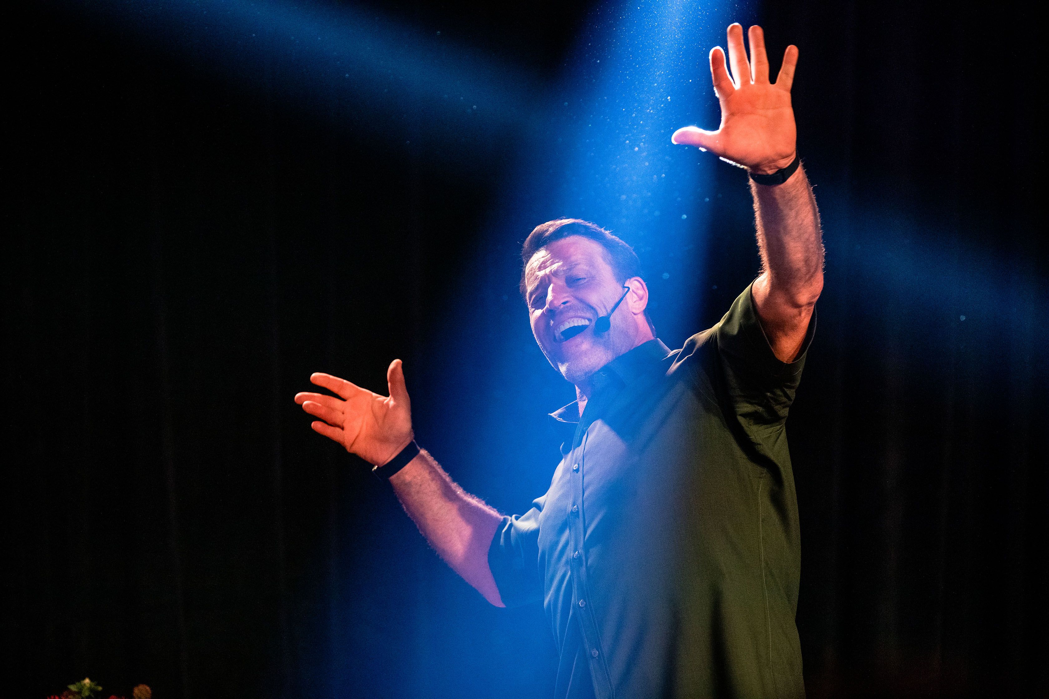 a man is standing on a stage with his hands in the air .