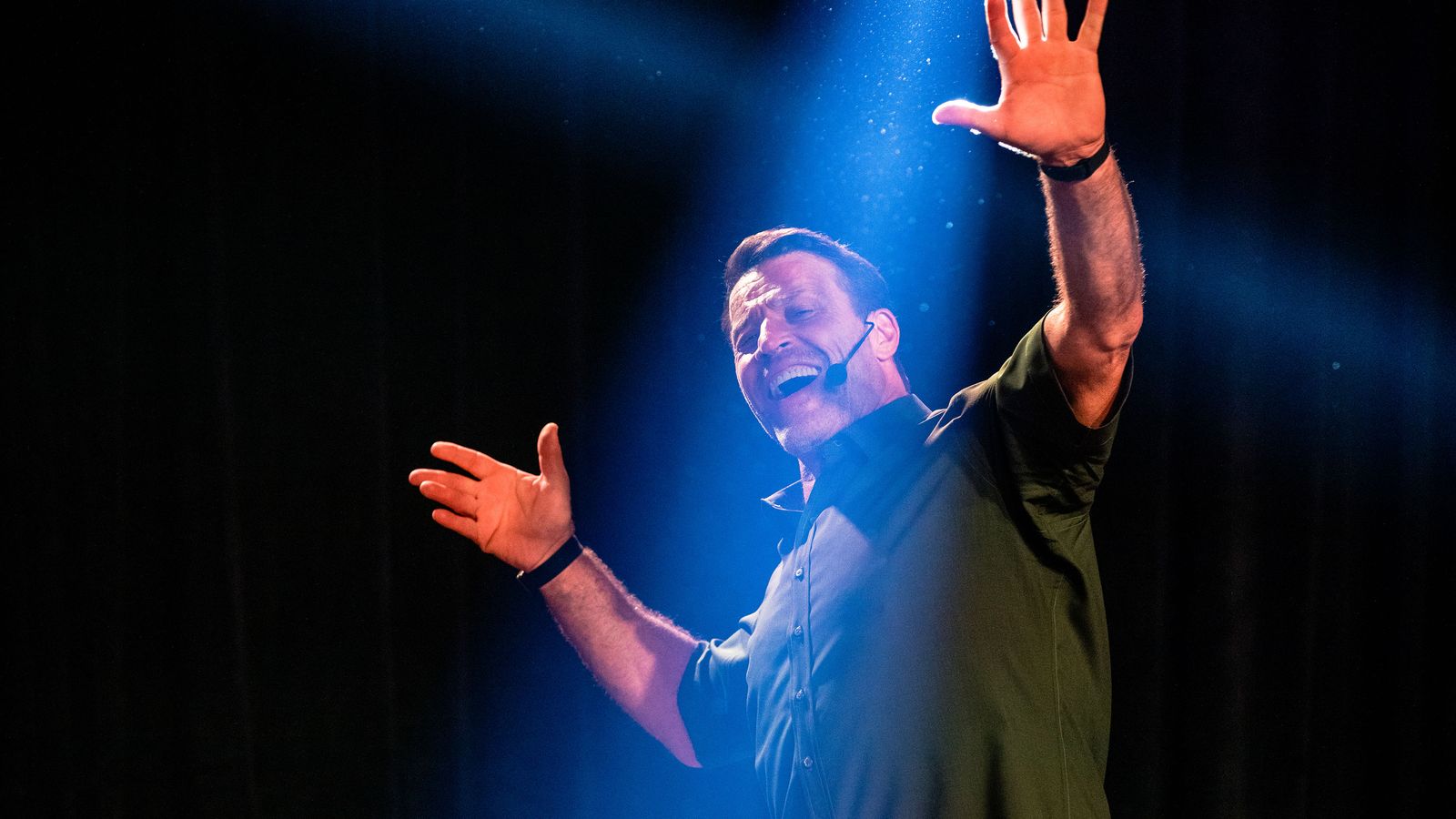 a man is standing on a stage with his hands in the air .
