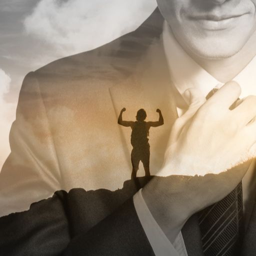 a man in a suit and tie is standing on top of a mountain with his arms outstretched .