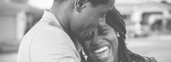 a black and white photo of a man and woman hugging each other and smiling .