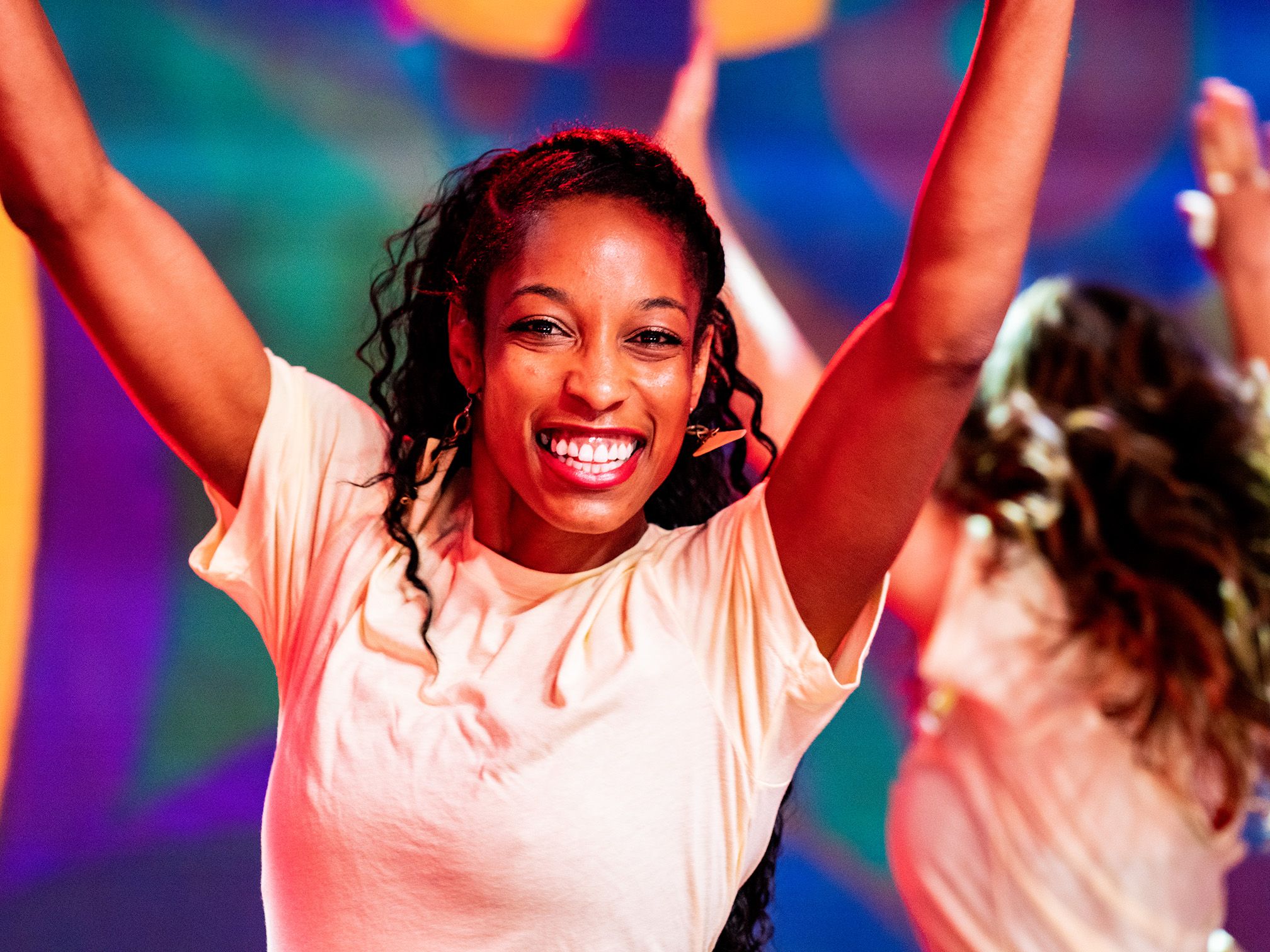 a woman is dancing and smiling with her arms in the air