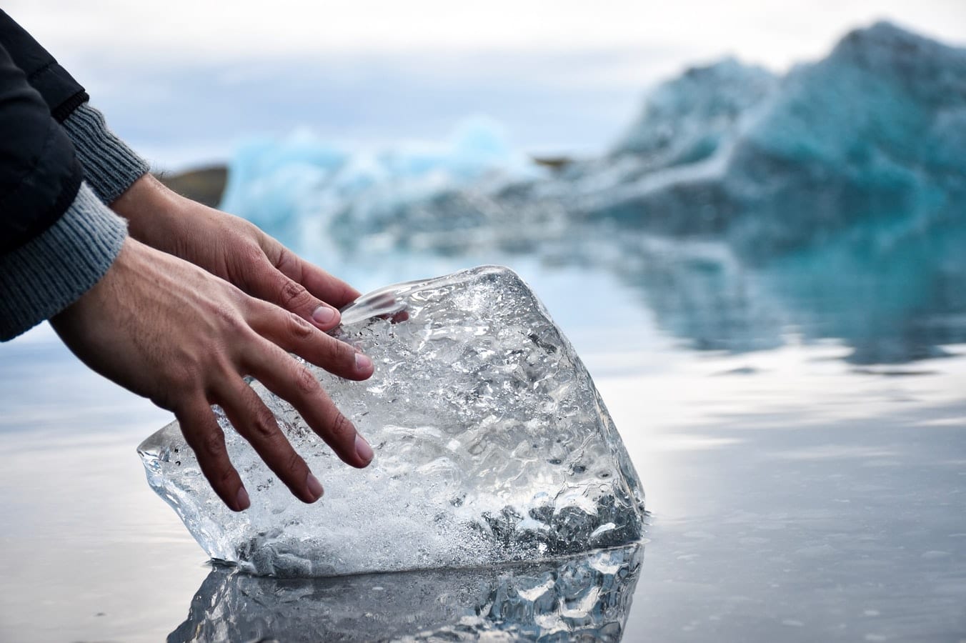 a person is touching a piece of ice in the water .