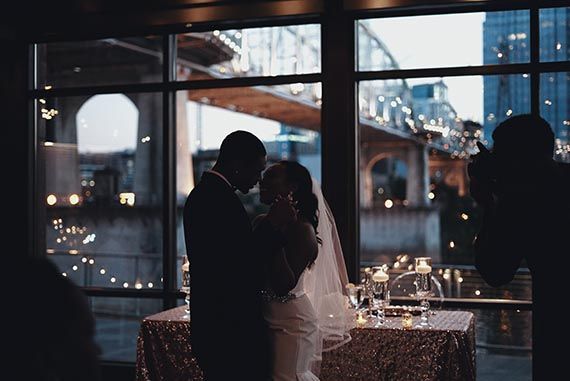 a bride and groom are dancing in front of a large window .