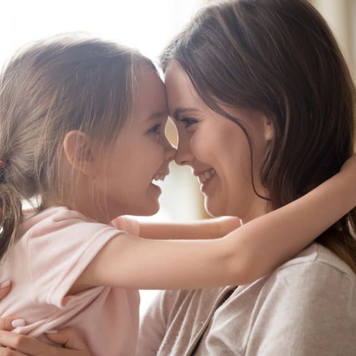 a woman and a little girl are hugging and touching their noses .