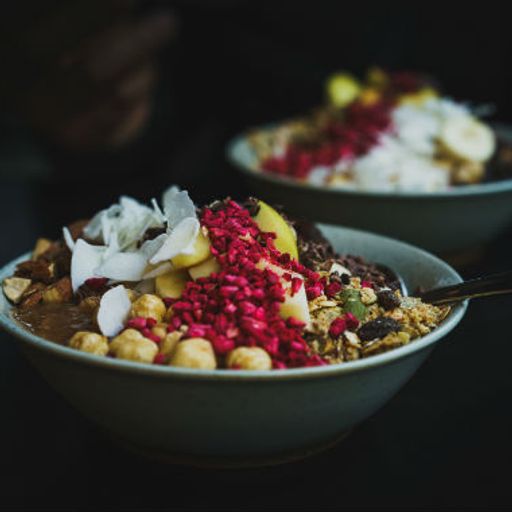 two bowls of food with a spoon in them are sitting on a table .