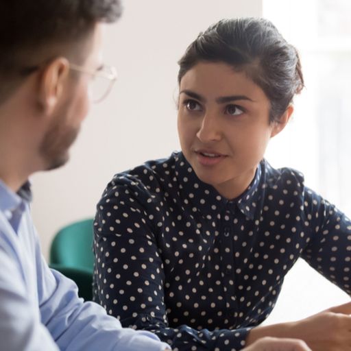 a man and a woman are sitting at a table having a conversation .