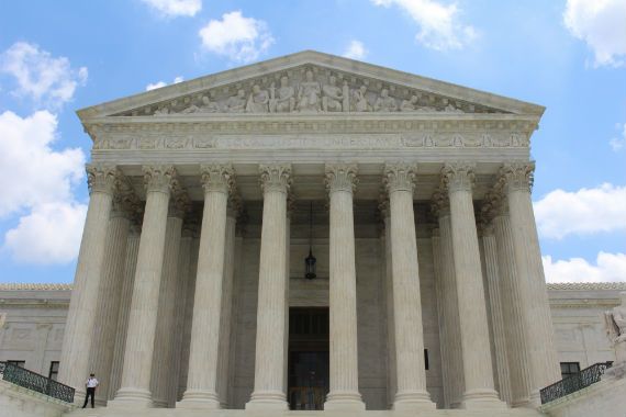 a man is standing on the steps of the supreme court building .