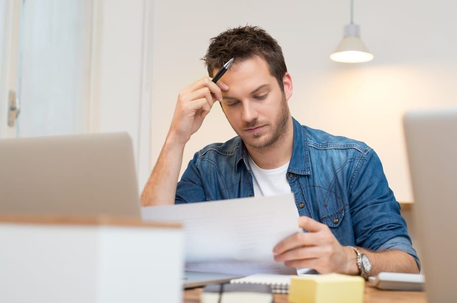 a man is sitting at a desk looking at a piece of paper .