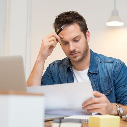 a man is sitting at a desk looking at a piece of paper .