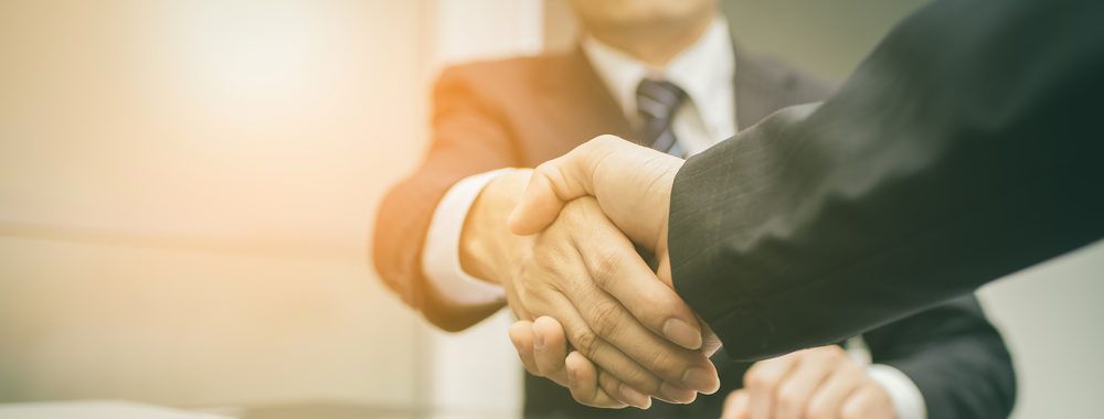 a man in a suit and tie is shaking hands with another man .