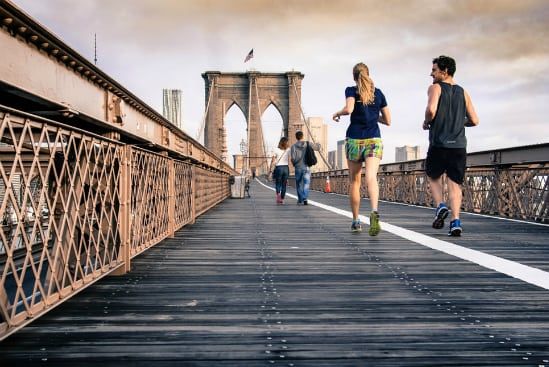 a group of people are running on a bridge in new york city .