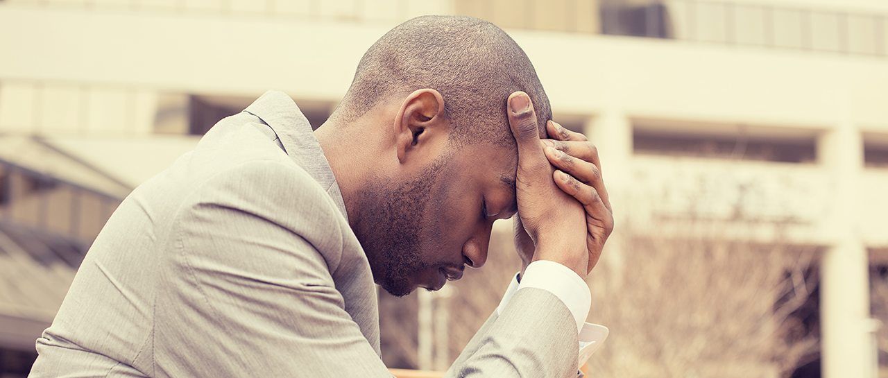 a man in a suit is holding his head in his hands .