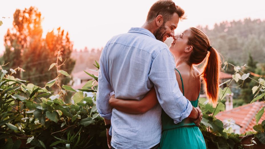 a man and a woman are hugging each other on a balcony .