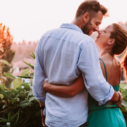 a man and a woman are hugging each other on a balcony .