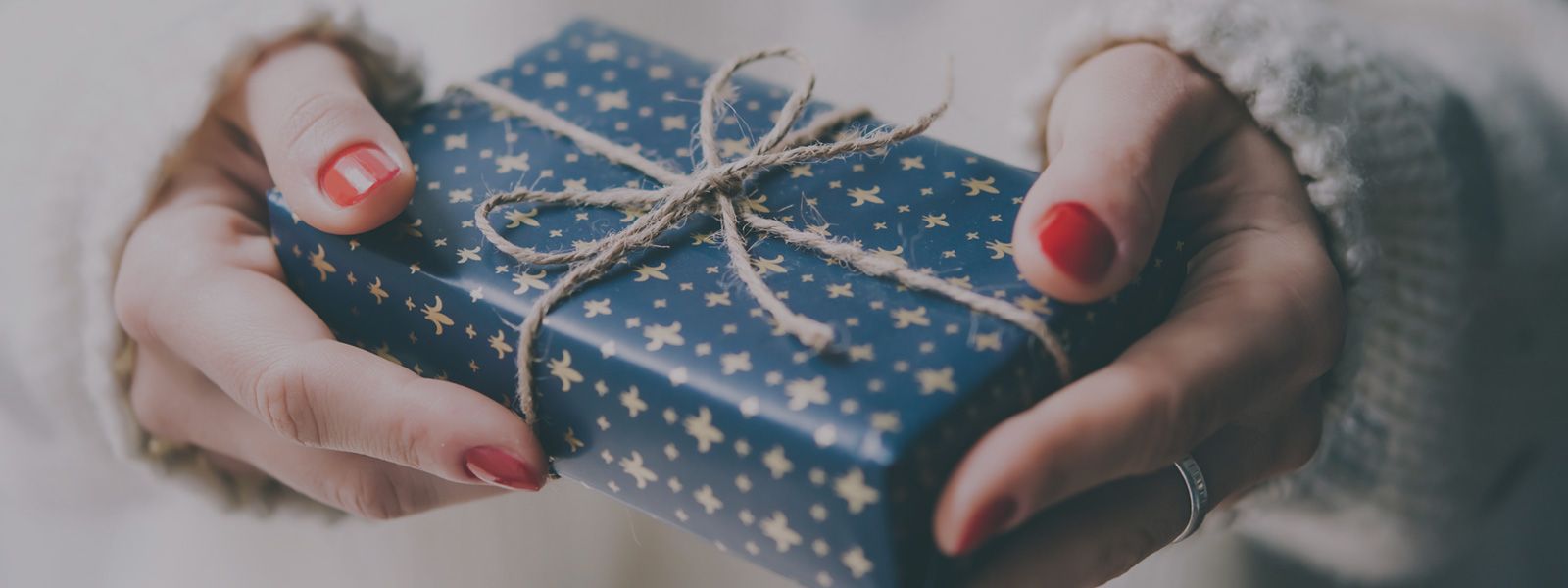 a woman is holding a blue wrapped gift in her hands .