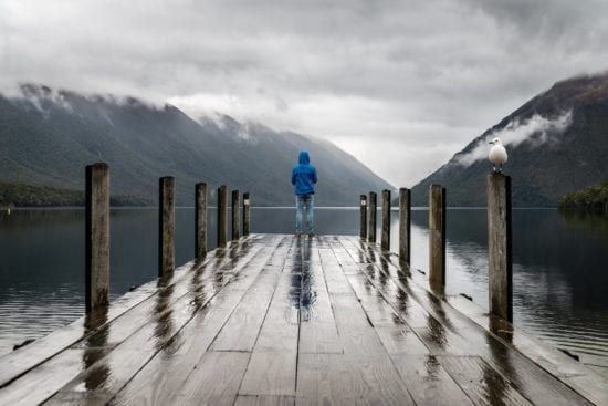 a person is standing on a wooden dock overlooking a lake .