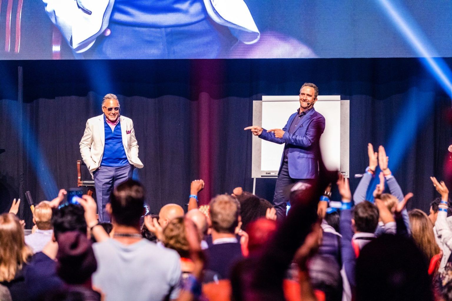 two men are standing on a stage in front of a crowd .