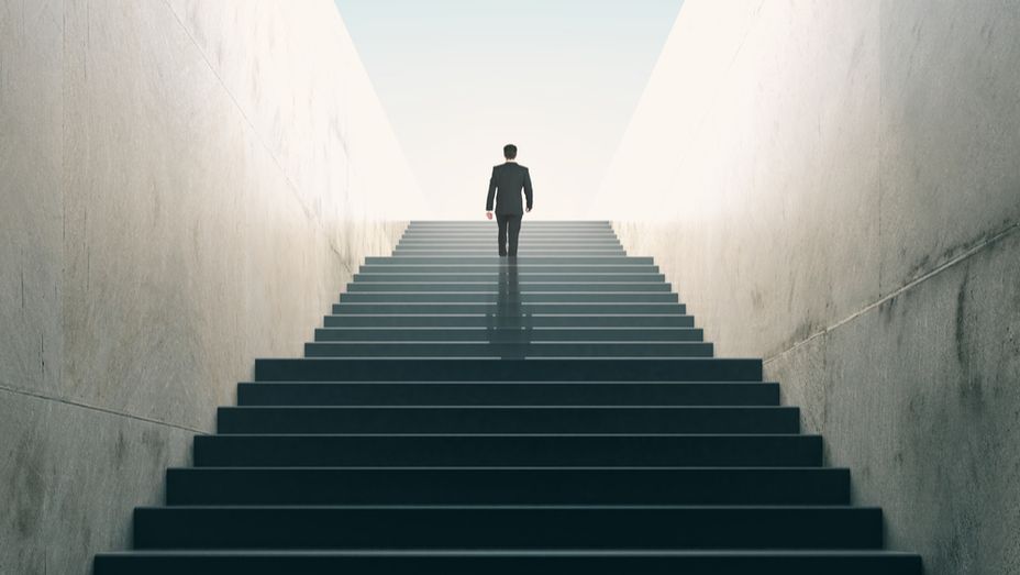 a man in a suit is walking up a set of stairs .