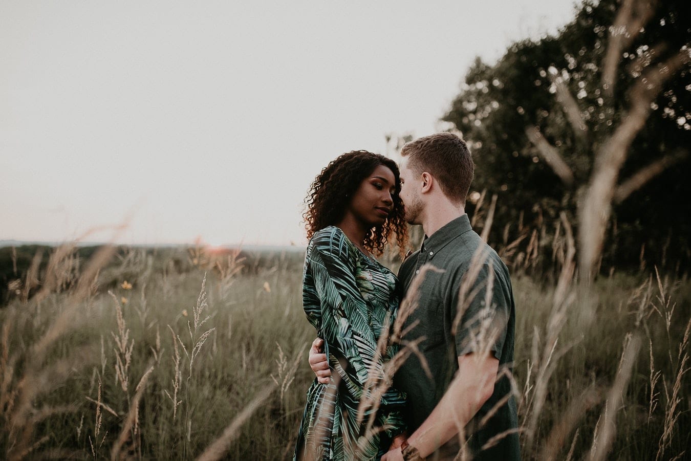 a man and a woman are standing in a field of tall grass .