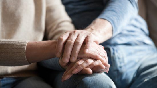 a man and a woman are holding hands while sitting on a couch .