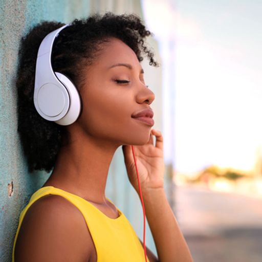 a woman wearing headphones is leaning against a wall .
