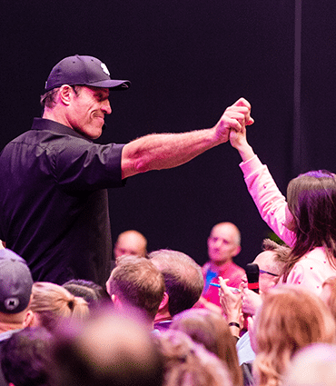 Stop living in fear of being hurt image of Tony Robbins grasping woman's hand in celebration