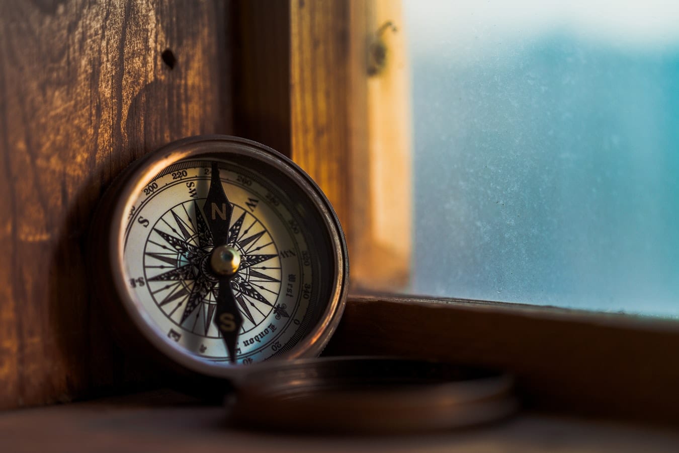 a compass is sitting on a wooden table next to a window .