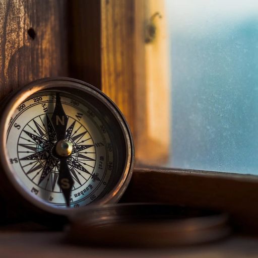 a compass is sitting on a wooden table next to a window .