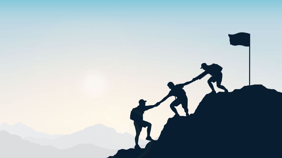 a man is helping another man climb a mountain .