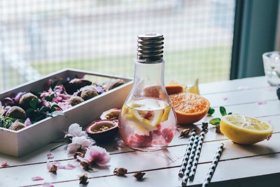 a light bulb shaped bottle filled with water and fruit on a table .