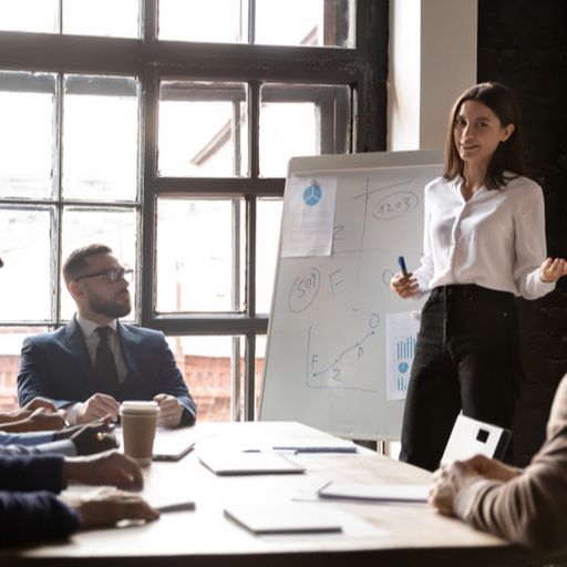 a woman is giving a presentation to a group of people sitting around a table .