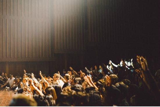 a crowd of people are raising their hands in the air at a concert .