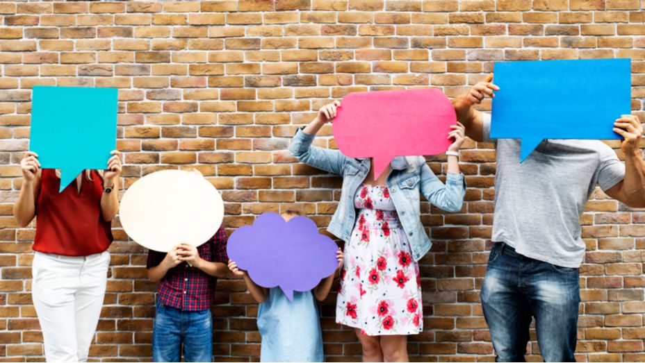 a group of people are holding speech bubbles in front of their faces .