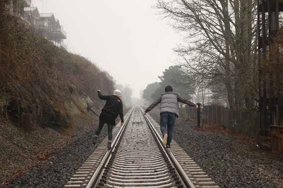two people are walking down train tracks in the fog .