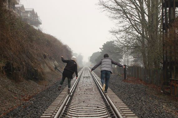 two people are walking down train tracks in the fog .