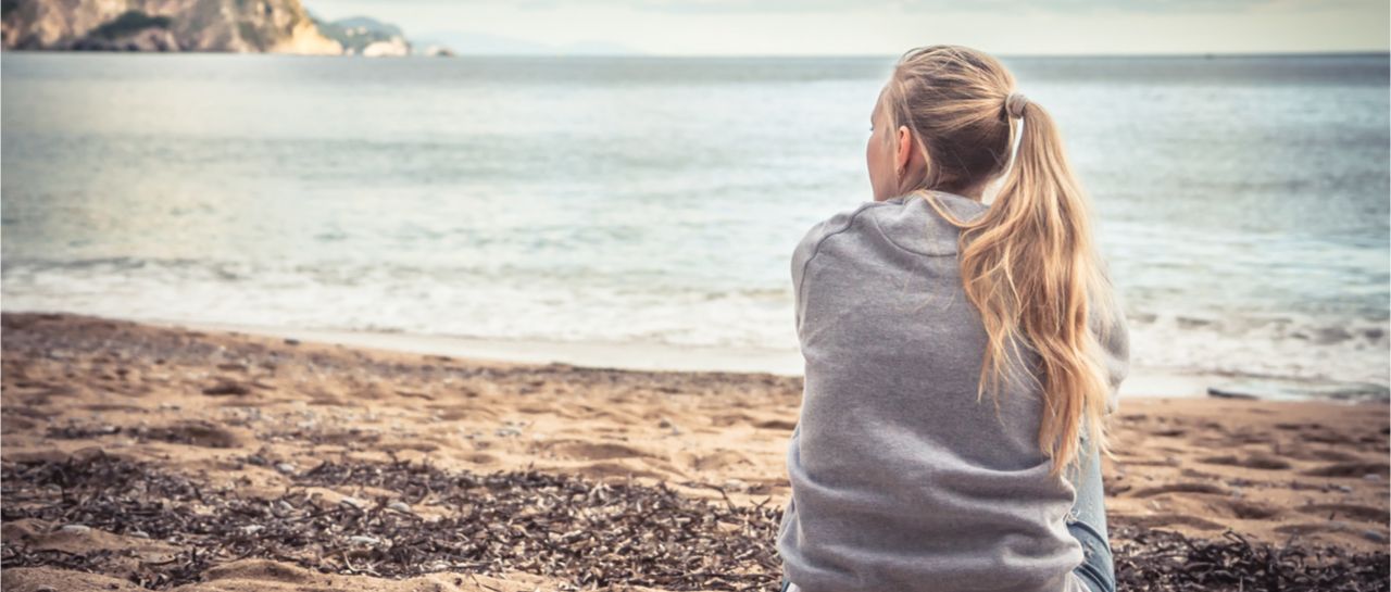 a woman is sitting on the beach looking at the ocean .