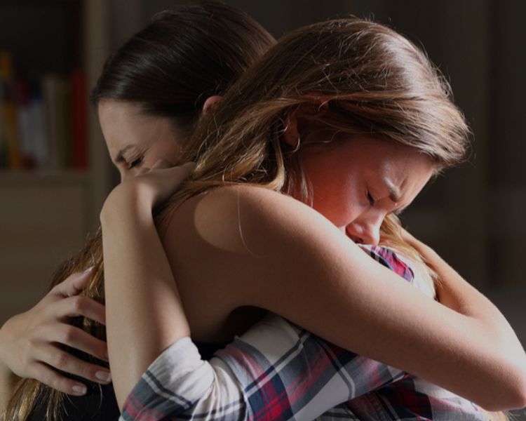 two women are hugging each other in a dark room .