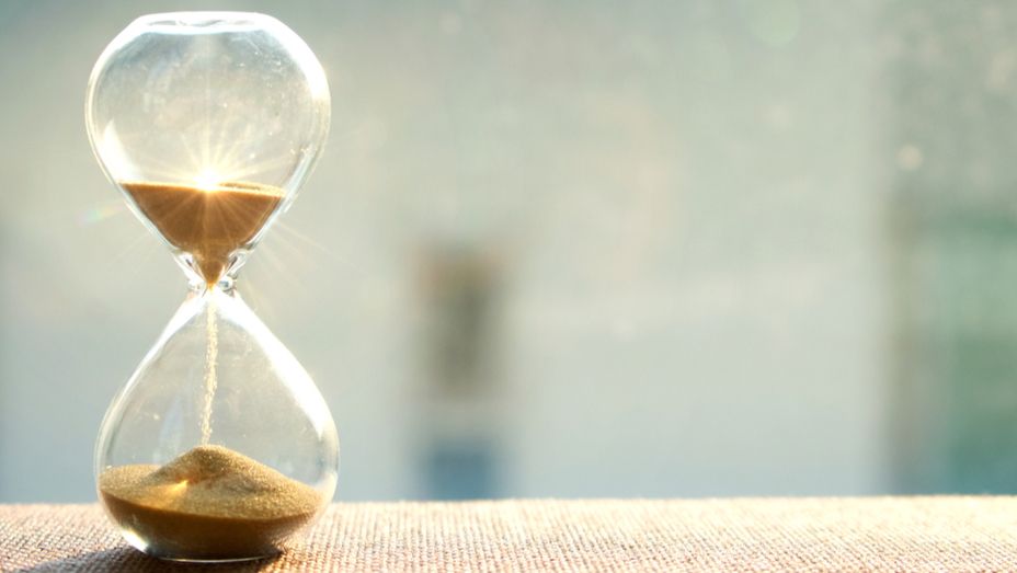 a hourglass is sitting on a table with the sun shining through it .