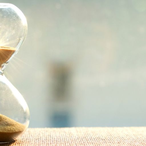 a hourglass is sitting on a table with the sun shining through it .