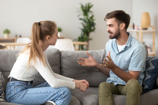 a man and a woman are sitting on a couch having a conversation .